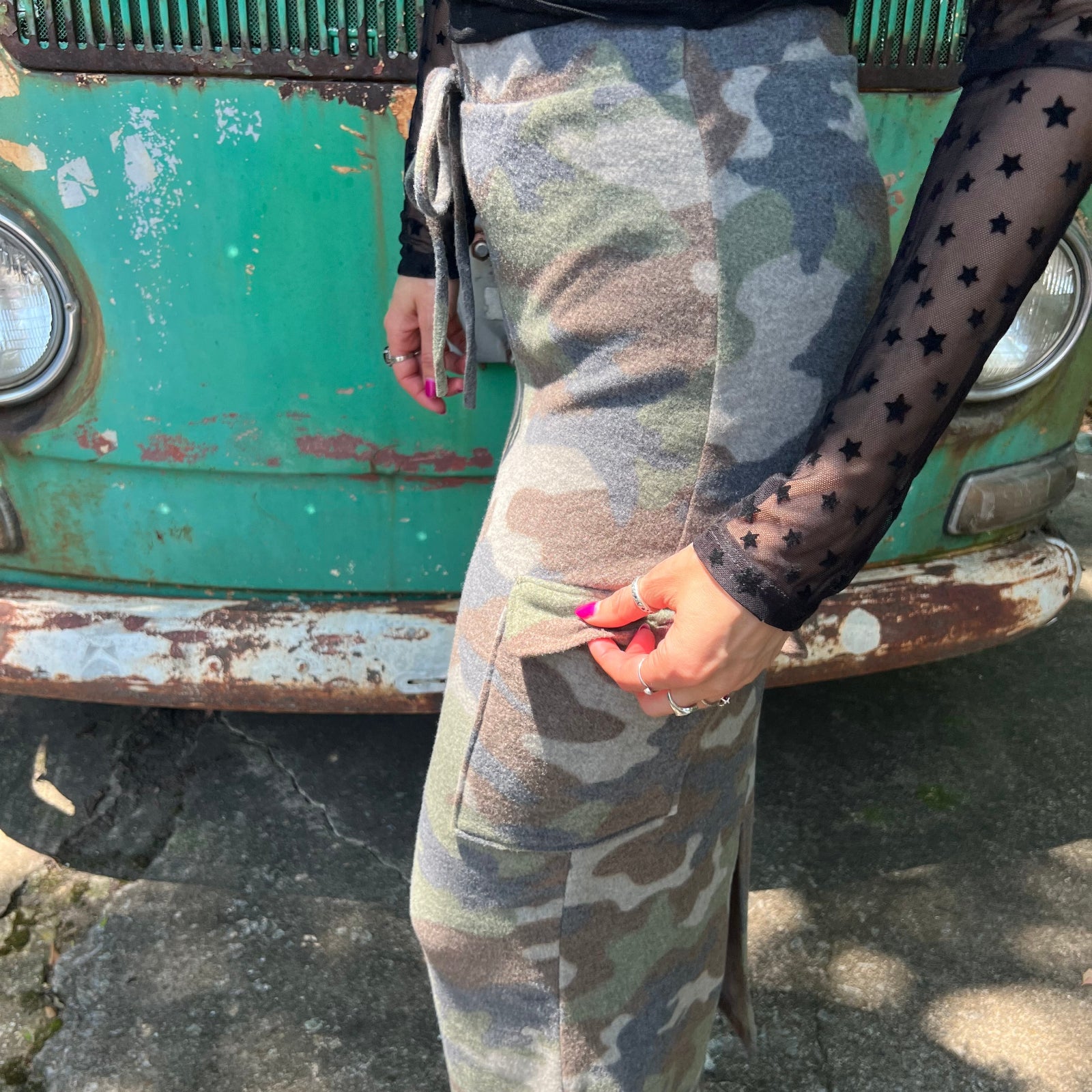 A woman wearing the Camo Cargo Skirt with a black star mesh top.