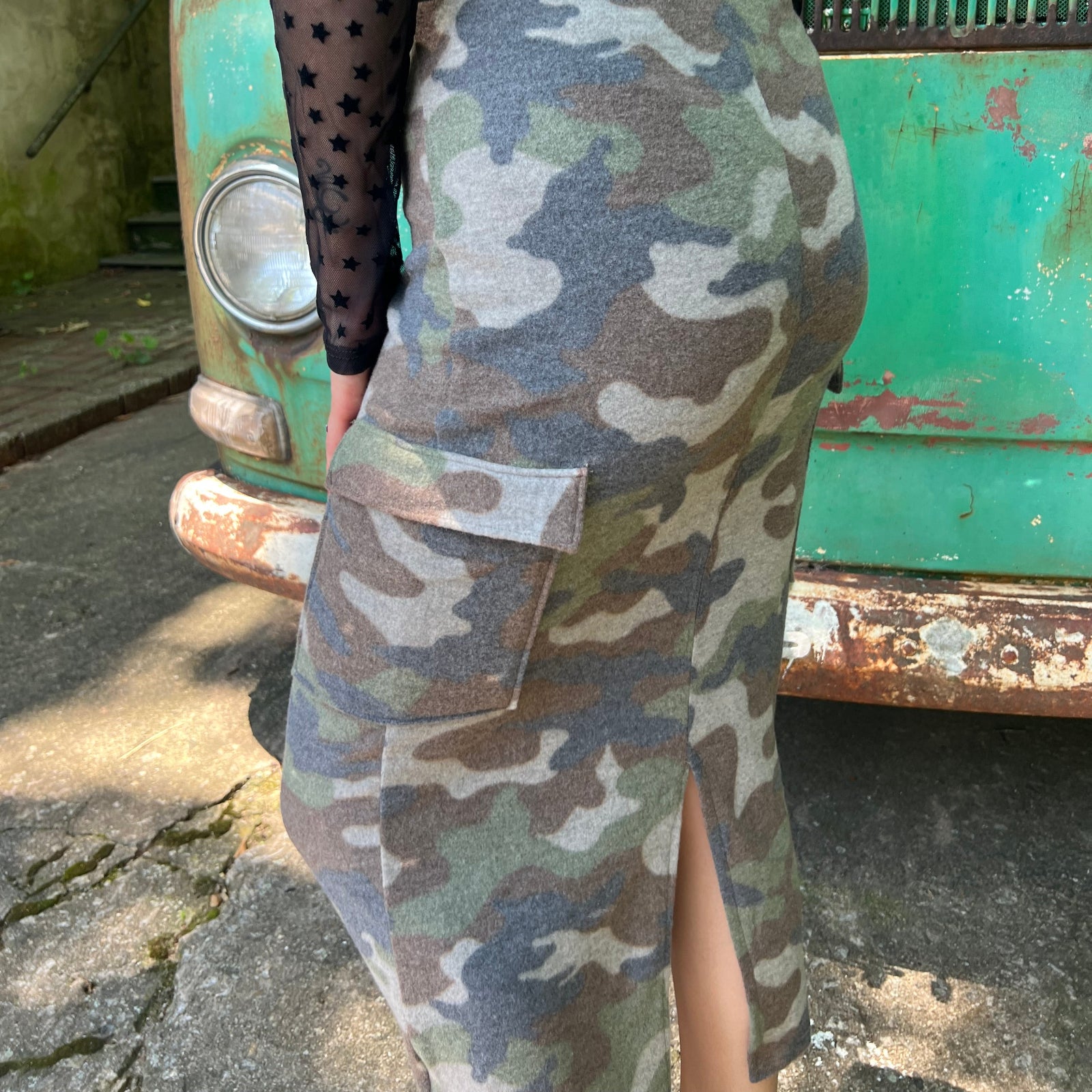 A woman wearing the Camo Cargo Skirt with a black star mesh top.