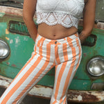 A woman wearing the Papaya Striped Washed Denim Bell Bottoms and a white bralette.