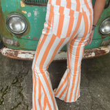A woman wearing the Papaya Striped Washed Denim Bell Bottoms and a white bralette.