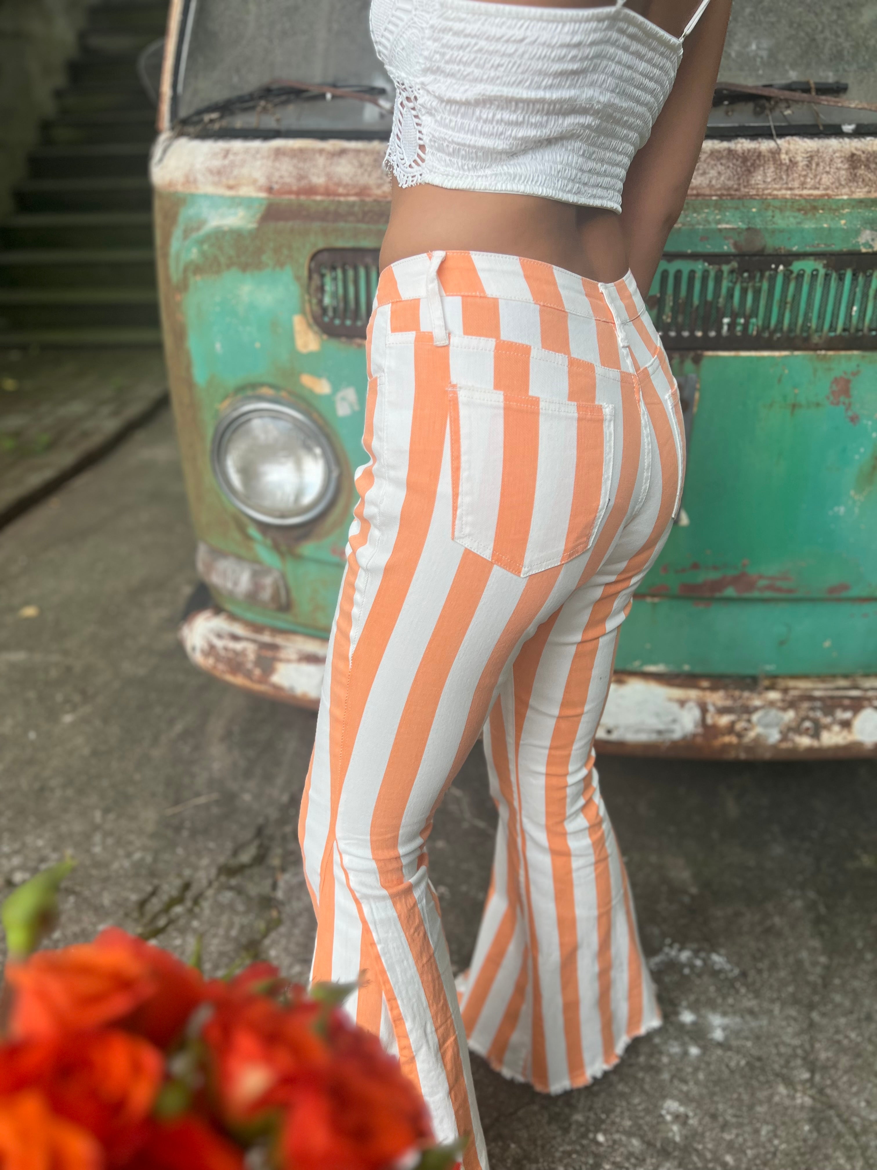 A woman wearing the Papaya Striped Washed Denim Bell Bottoms and a white bralette.