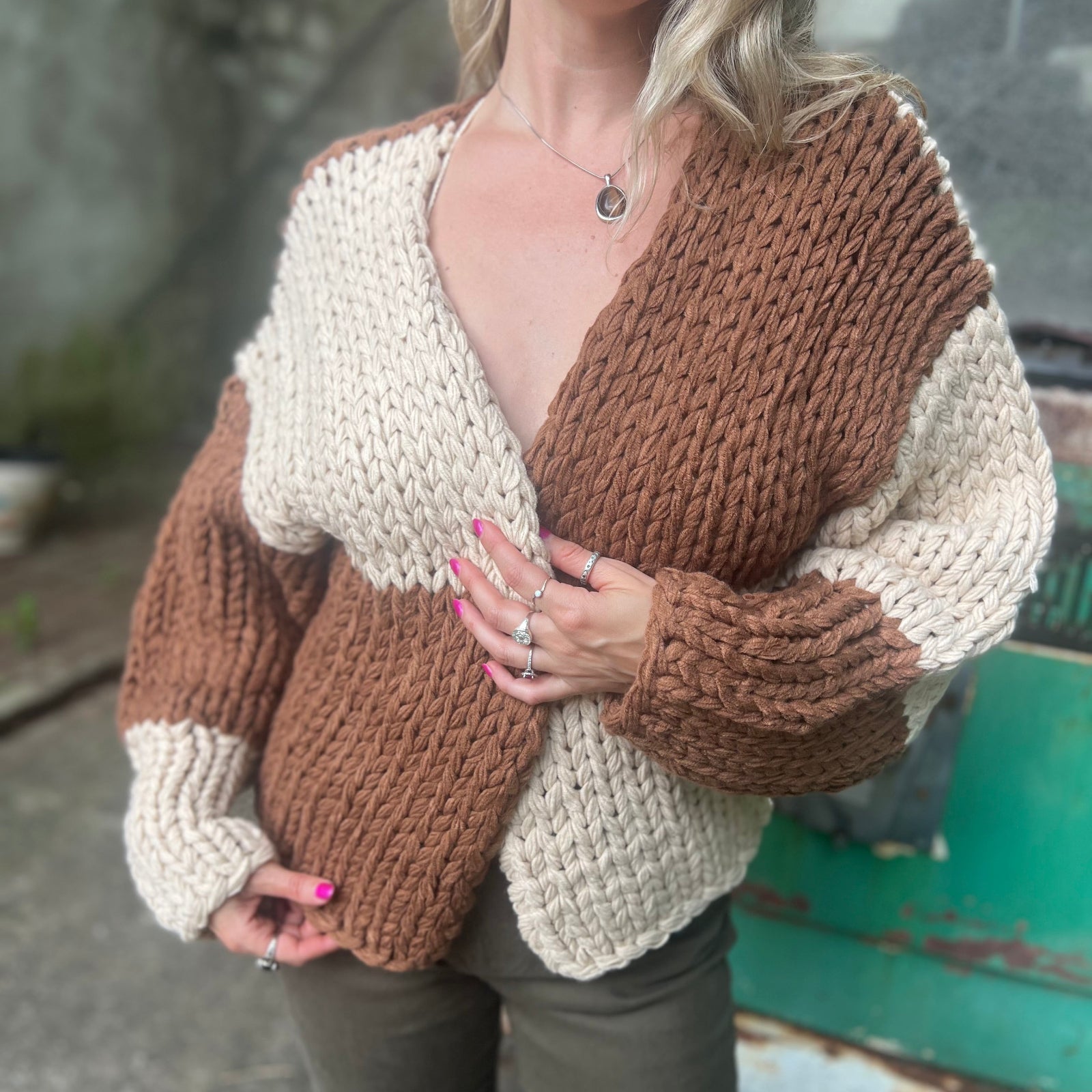 A woman wearing the Cream and Brown Color Block Chunky Knit Open Front Sweater Cardigan with a white crochet top.