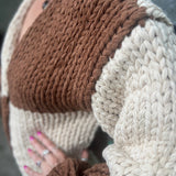 A woman wearing the Cream and Brown Color Block Chunky Knit Open Front Sweater Cardigan with a white crochet top.