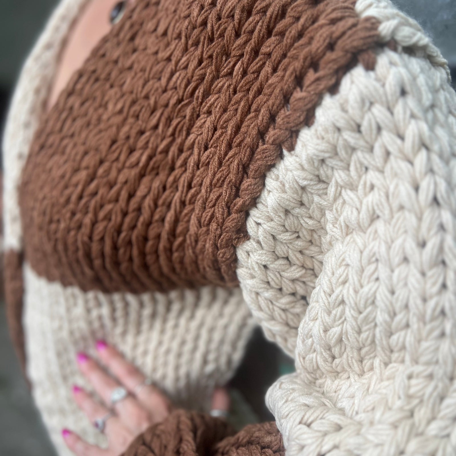 A woman wearing the Cream and Brown Color Block Chunky Knit Open Front Sweater Cardigan with a white crochet top.