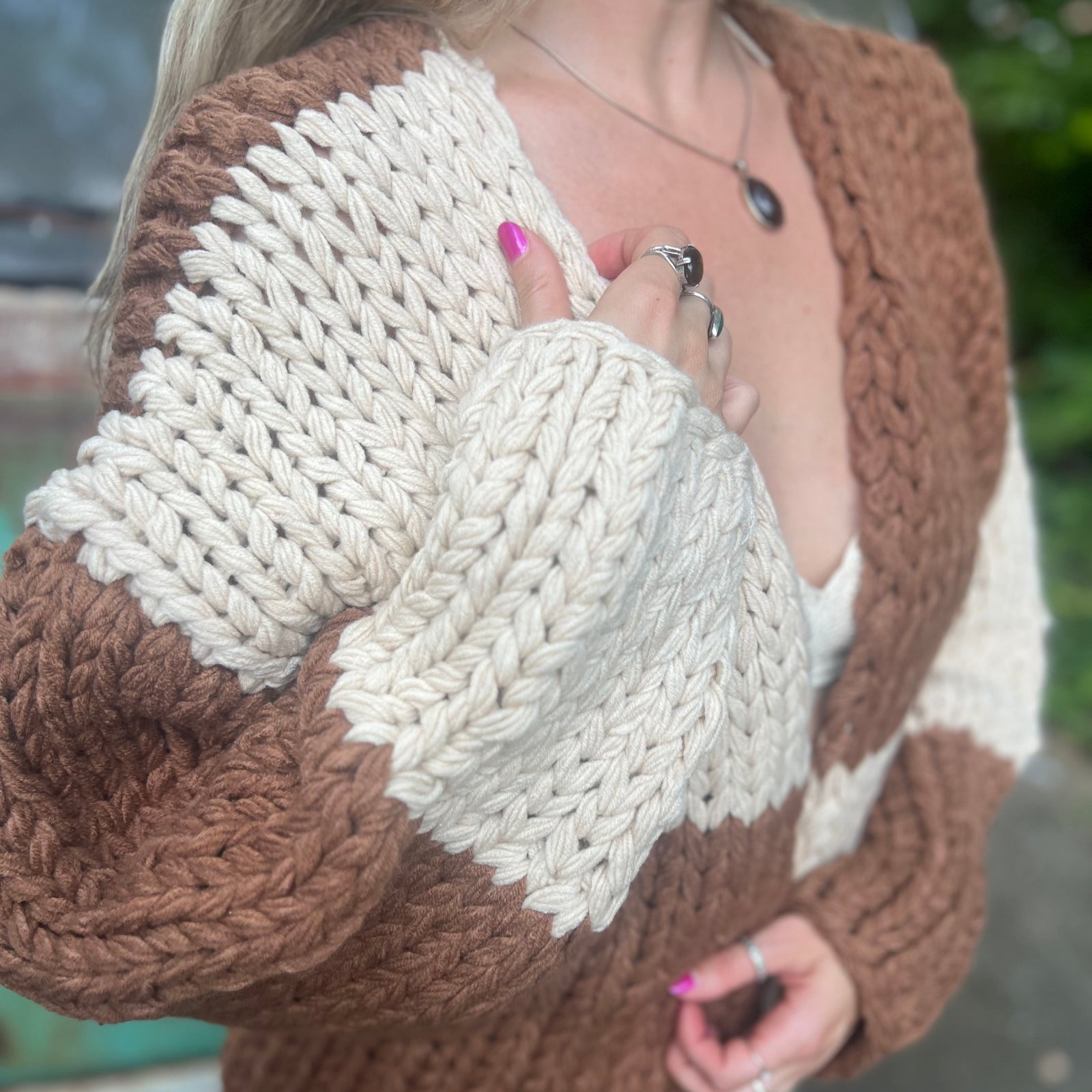 A woman wearing the Cream and Brown Color Block Chunky Knit Open Front Sweater Cardigan with a white crochet top.