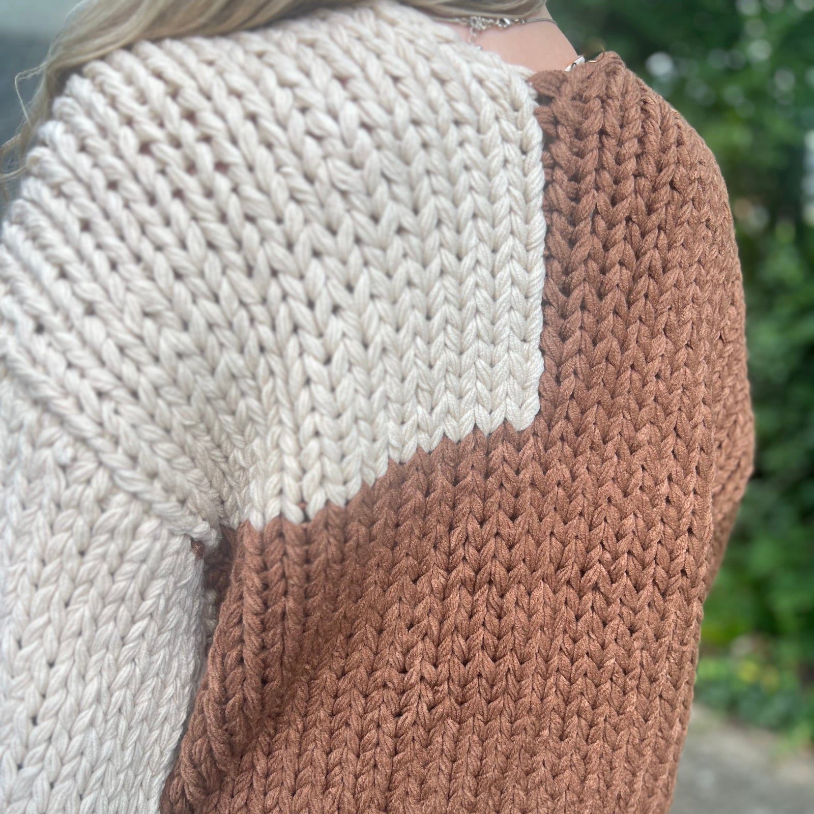 A woman wearing the Cream and Brown Color Block Chunky Knit Open Front Sweater Cardigan with a white crochet top.