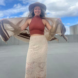 A woman wearing the Crochet-Knit Lace Fringe Maxi Skirt with a red top and a kimono.
