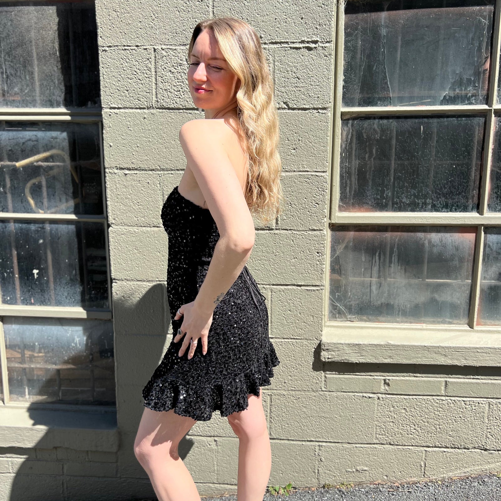 A woman wearing the espresso Sequin Lace-Up Back Strapless Mini Dress.