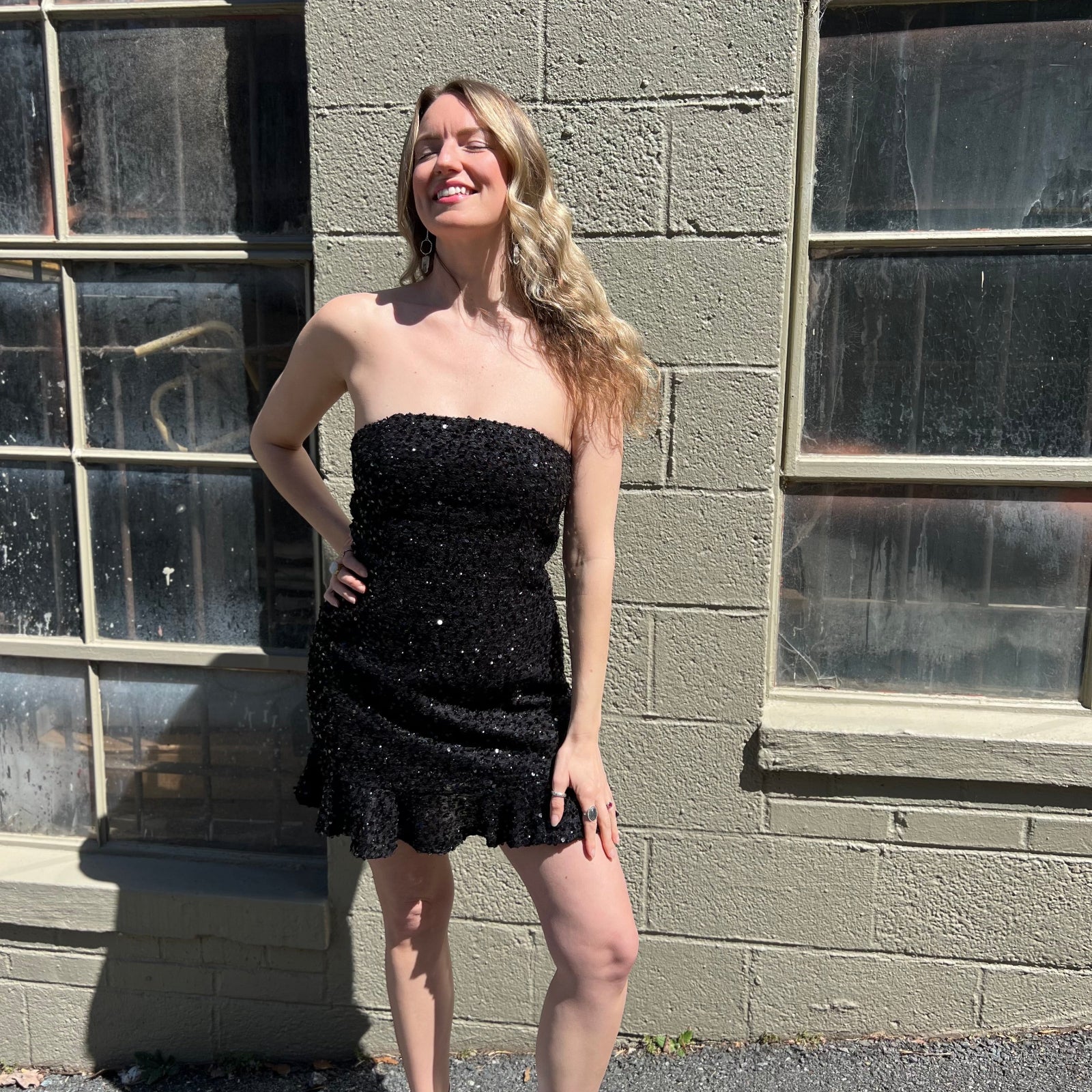 A woman wearing the black Sequin Lace-Up Back Strapless Mini Dress.