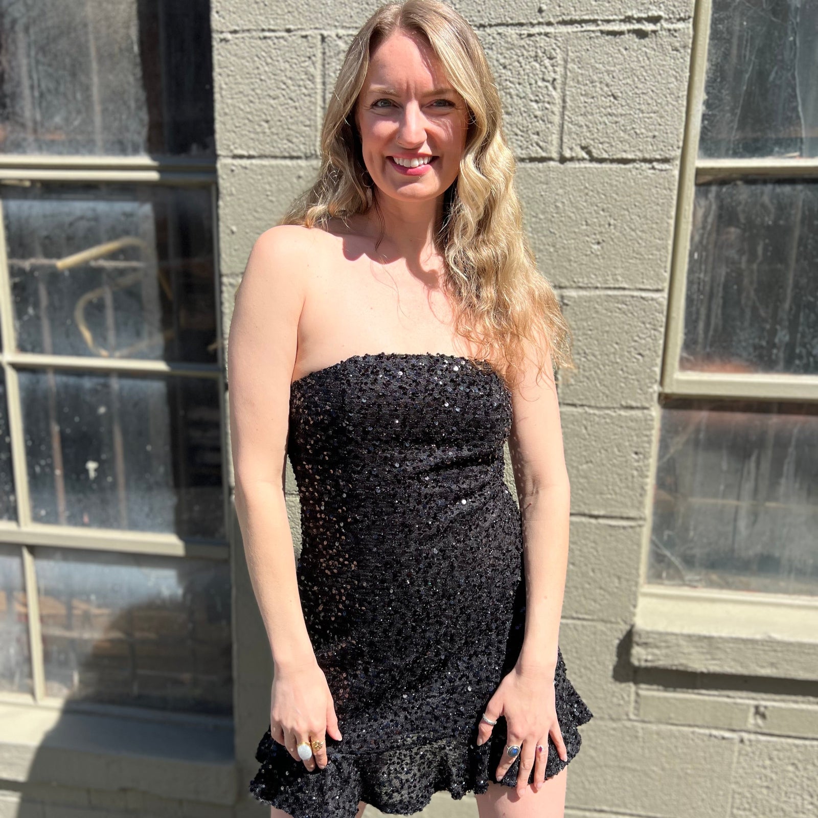 A woman wearing the espresso Sequin Lace-Up Back Strapless Mini Dress.