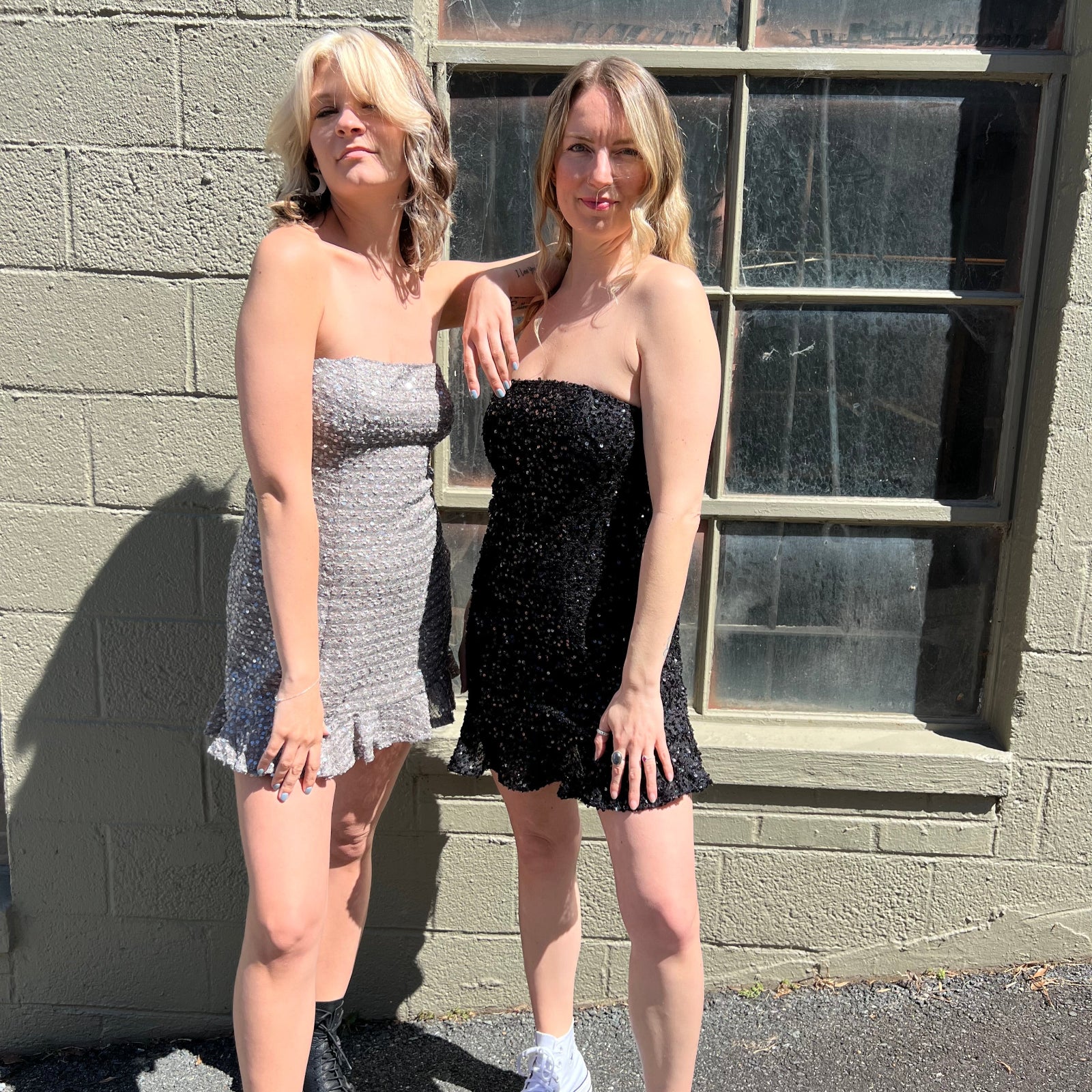 Two women wearing the espresso and black Sequin Lace-Up Back Strapless Mini Dresses.