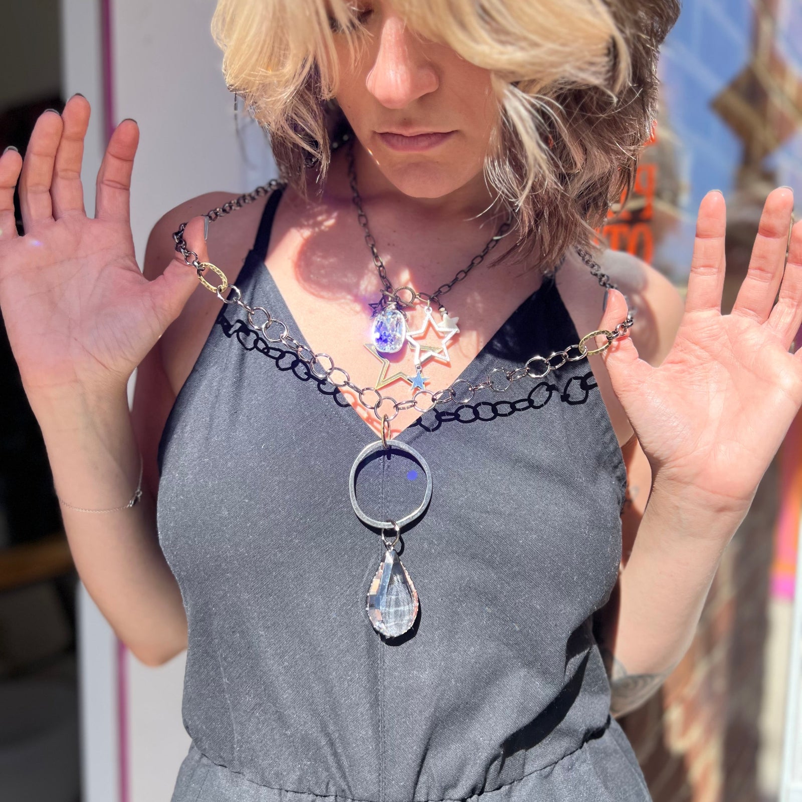 A woman wearing and holding the Gorgeous Gunmetal Crystal 32" Necklace out a little bit with a black dress.