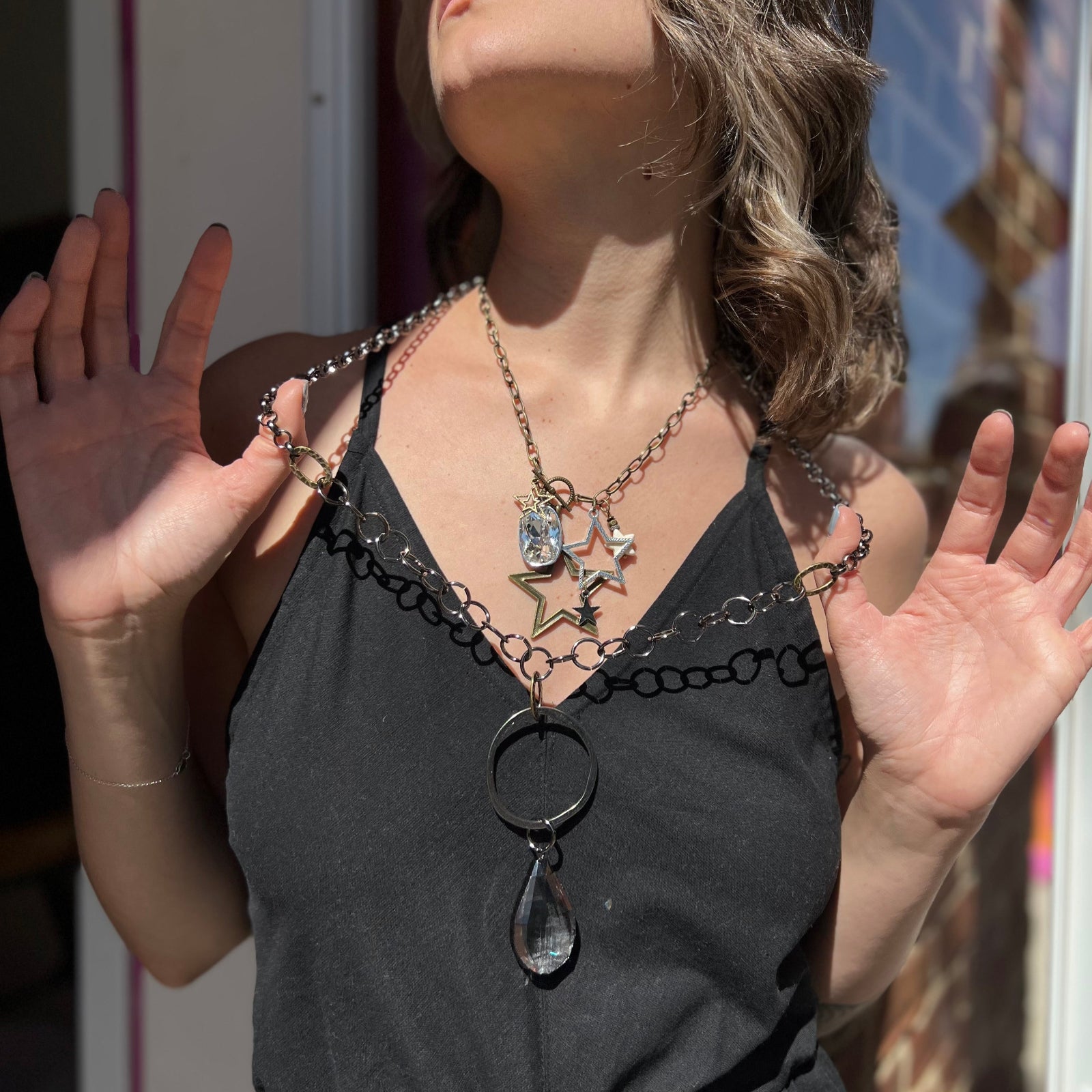 A woman wearing and holding the Gorgeous Gunmetal Crystal 32" Necklace out a little bit with a black dress.