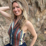 Close-up of woman wearing moon phase hat and striped crop top smiling in front of a rocky background