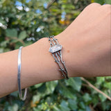 Someone wearing the Silver Thorn Cuff Bracelet in front of a green bush.