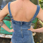 A woman wearing the medium wash Washed Western Buckle Embroidered Romper in front of a vintage teal Volkswagen bus.