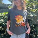 A woman wearing the Season Of The Witch Halloween Retro Cotton T-Shirt with jeans in front of some greenery.