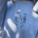 An up-close image of the embroidered graphic on the Halloween Skeletons Gray Cotton Crewneck Sweatshirt