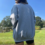 A woman wearing the Halloween Skeletons Gray Cotton Crewneck Sweatshirt with black shorts, showing off the back.