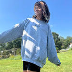 A woman wearing the Halloween Skeletons Gray Cotton Crewneck Sweatshirt with black shorts.