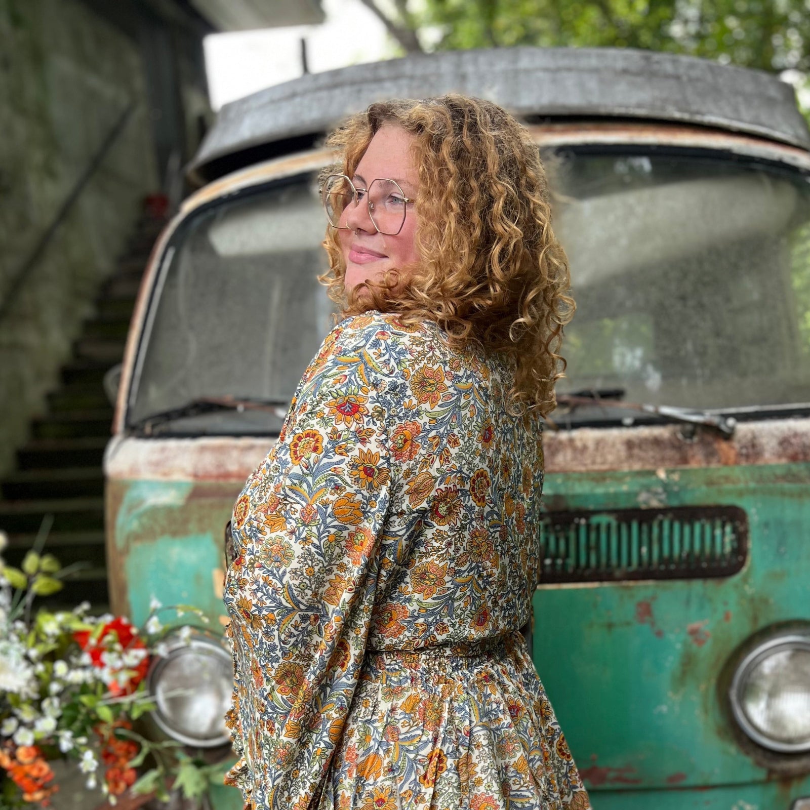 A woman wearing the orange and cream Hippie Bohemian Bell Sleeve Wrap Top with black pants in front of a rusted vintage Volkswagen bus.