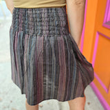 A woman wearing the agate Granny Square Mini Skirt with a tan top.