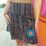 A woman wearing the agate Granny Square Mini Skirt with a tan top.