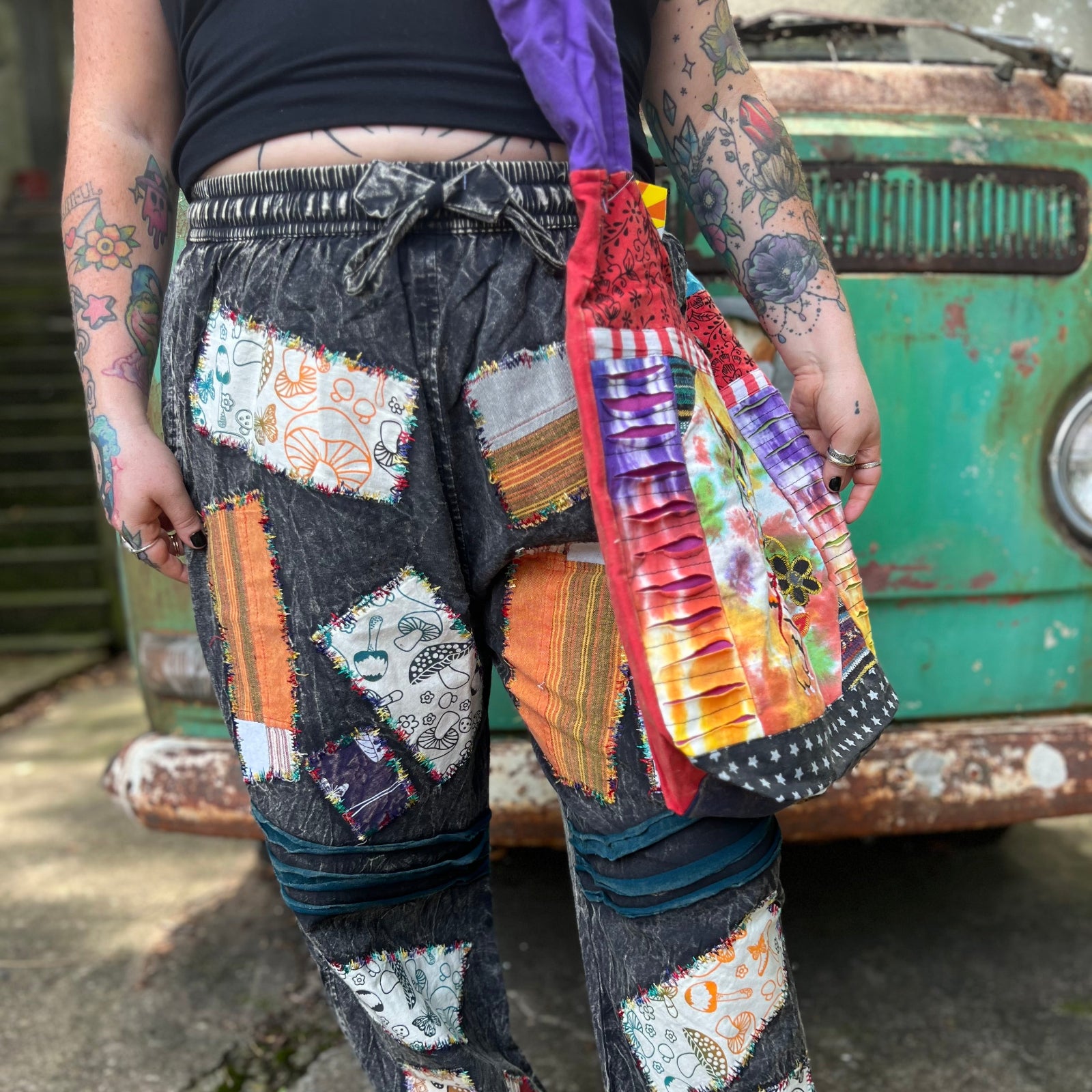 An up-close image of someone wearing the Cotton Tie Dye Cat Crossbody Bag in front of the vintage Volkswagen bus.