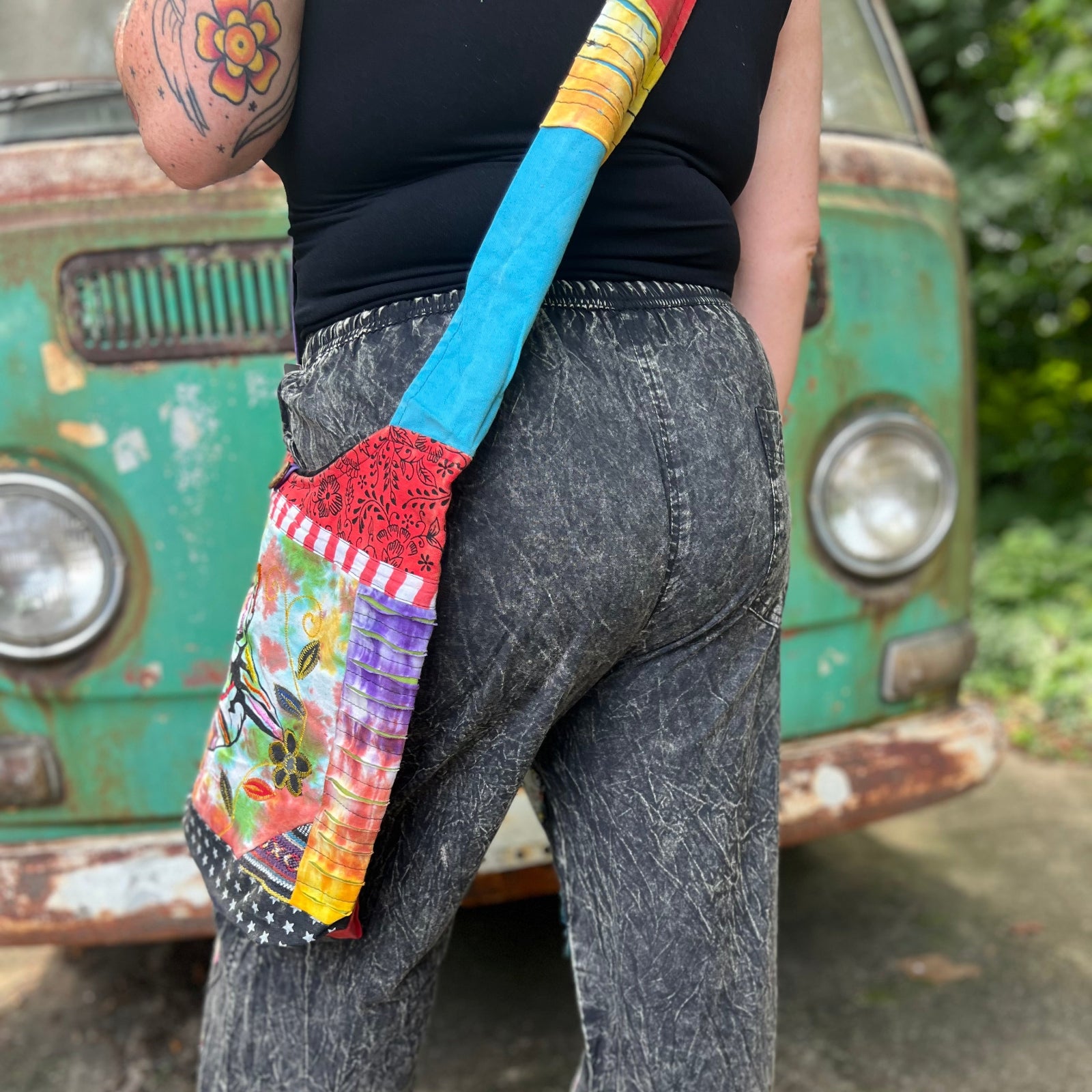 An up-close image of someone wearing the Cotton Tie Dye Cat Crossbody Bag in front of the vintage Volkswagen bus.
