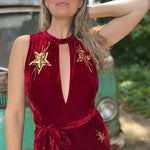 A woman wearing the burgundy Suede Sequin Embellished Embroidered Bootcut Jumpsuit in front of a teal vintage Volkswagen bus.