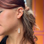 Someone wearing the brass Quartz Crystal Drop Earrings.