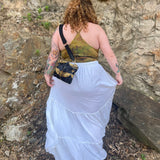 A woman wearing a tie dye top with the white Homespun Tiered Maxi Skirt in front of a rock wall.