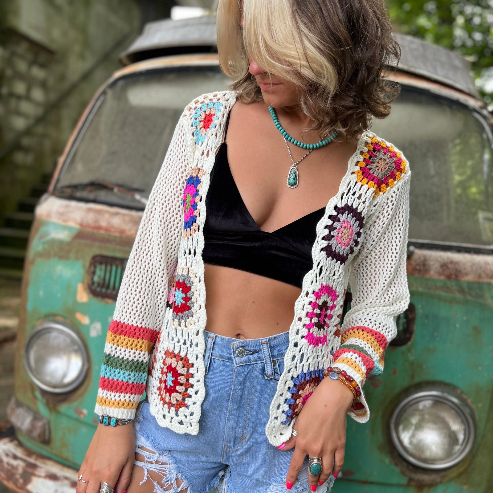 Someone wearing the Bohemian Rainbow Crochet Cardigan in front of an old teal Volkswagen bus.
