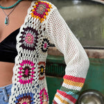 An up-close image of someone wearing the Bohemian Rainbow Crochet Cardigan in front of an old teal Volkswagen bus.