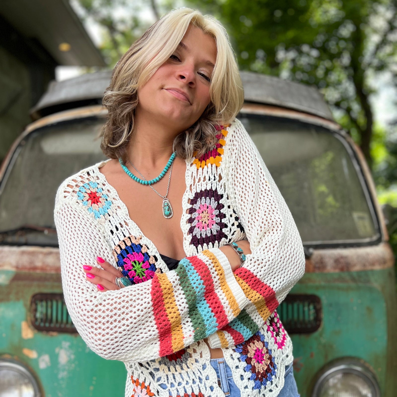 Someone wearing the Bohemian Rainbow Crochet Cardigan in front of an old teal Volkswagen bus.