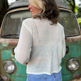The back of someone wearing the Bohemian Rainbow Crochet Cardigan in front of an old teal Volkswagen bus.