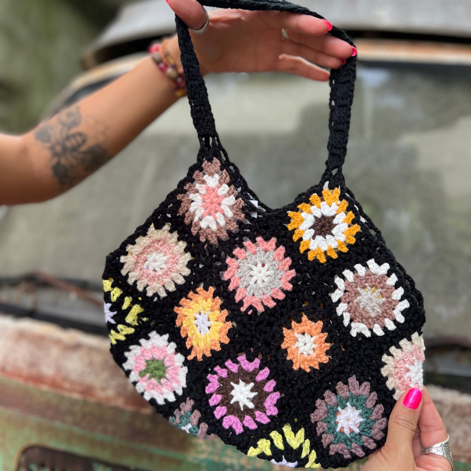 Someone holding the black Bohemian Handmade Crochet Bag in front of an old teal Volkswagen bus.