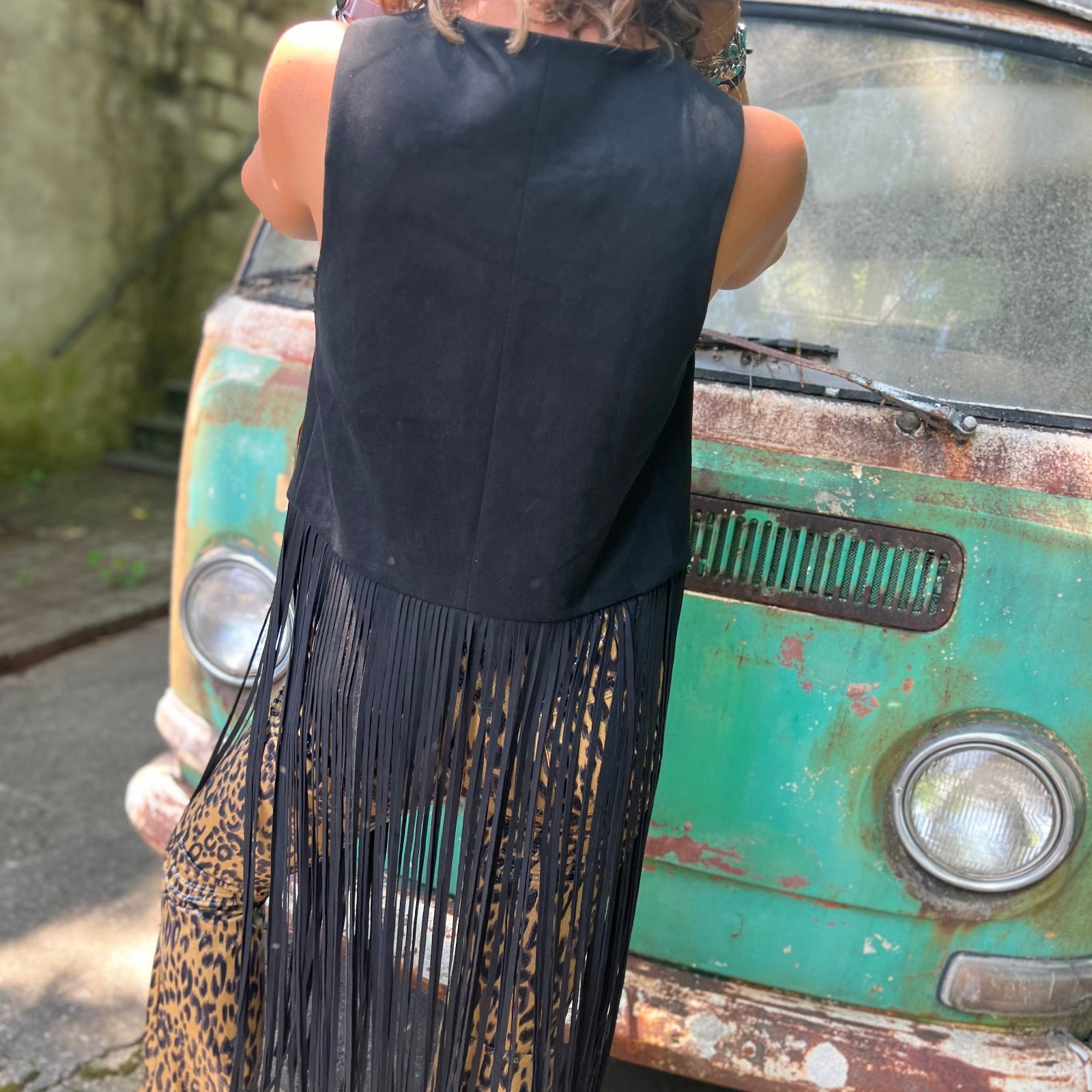 A woman wearing the black Faux Suede Long Fringe Western Vest.