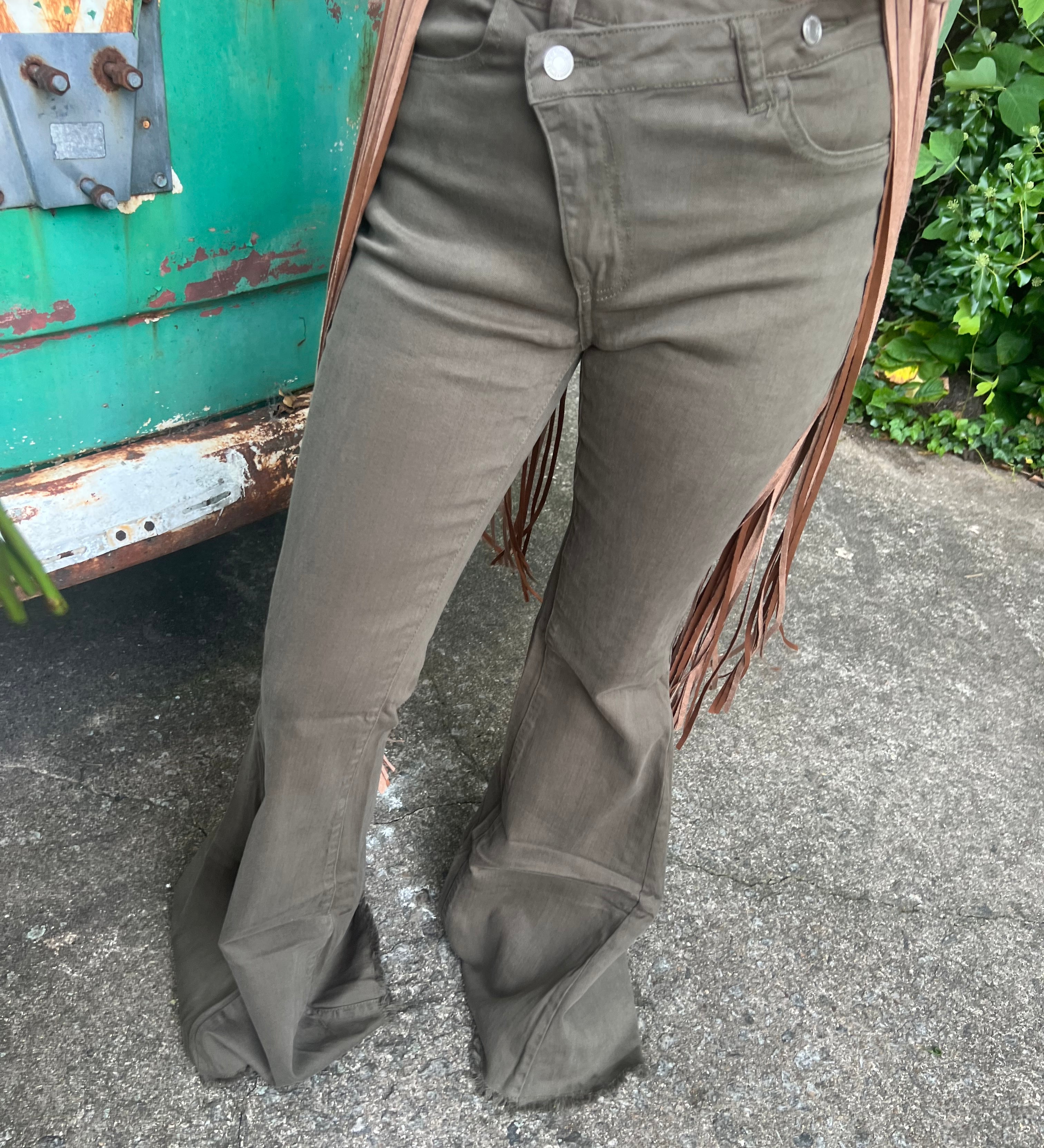 Someone wearing the Olive Criss Cross Upsized Bell Bottom Jean with a fringe vest.