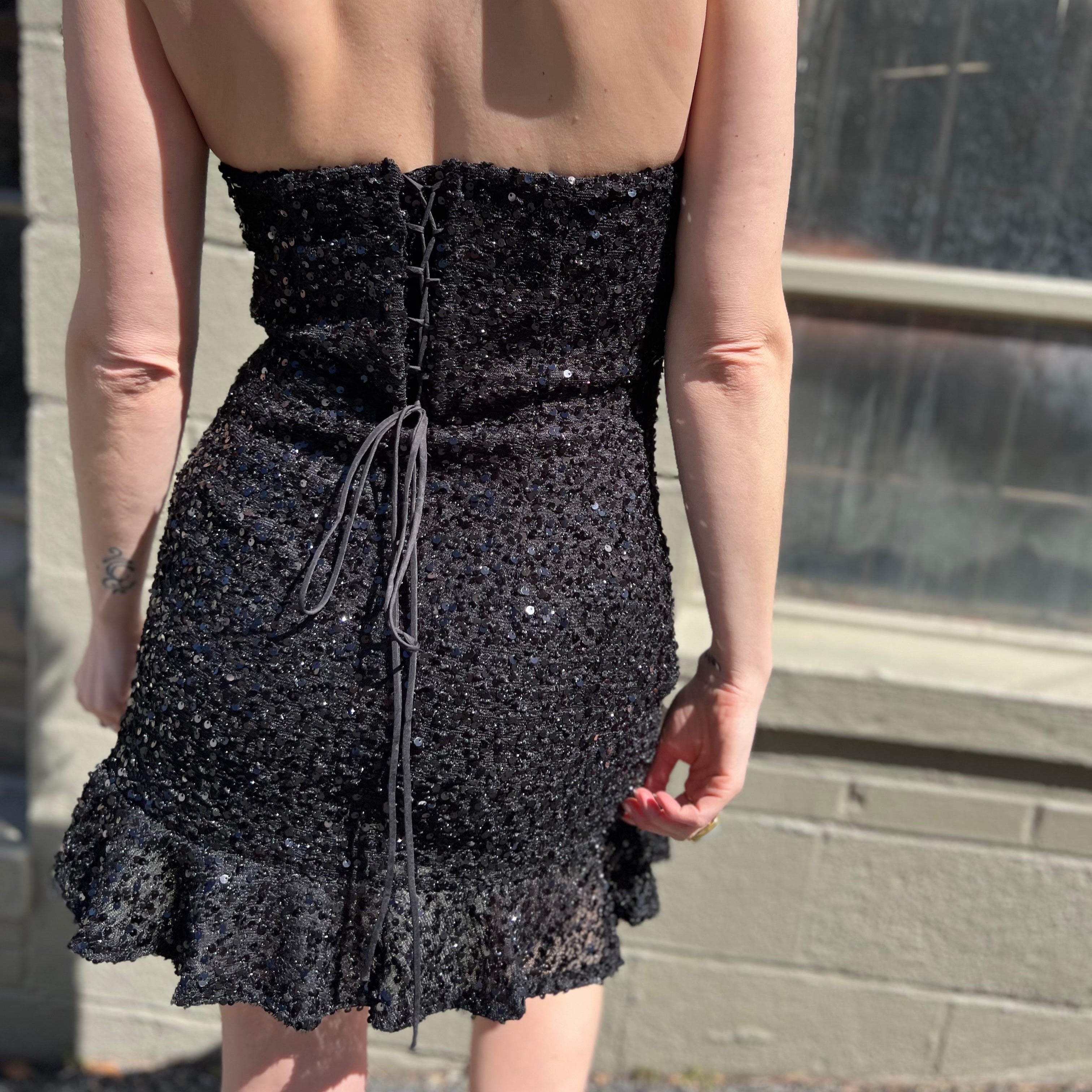 A woman wearing the espresso Sequin Lace-Up Back Strapless Mini Dress.