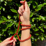 model holding red jasper mala weaved in her hands on a greenery background