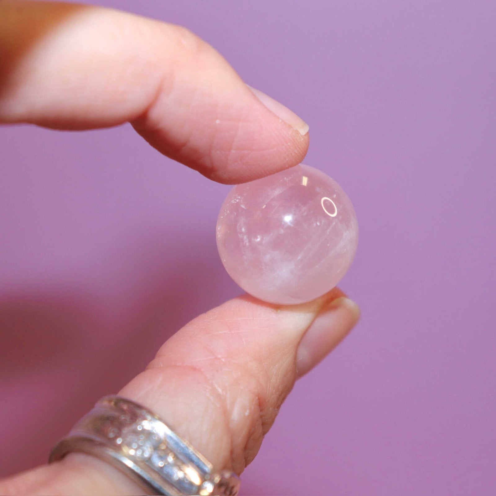 hand holding a rose quartz crystal marble