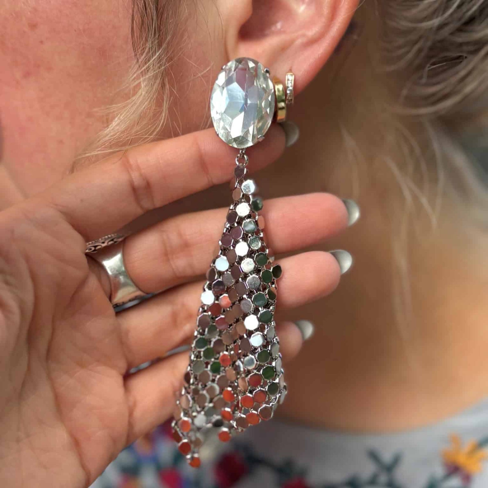 Close-up of silver disco earrings with crystal stud and mesh fringe