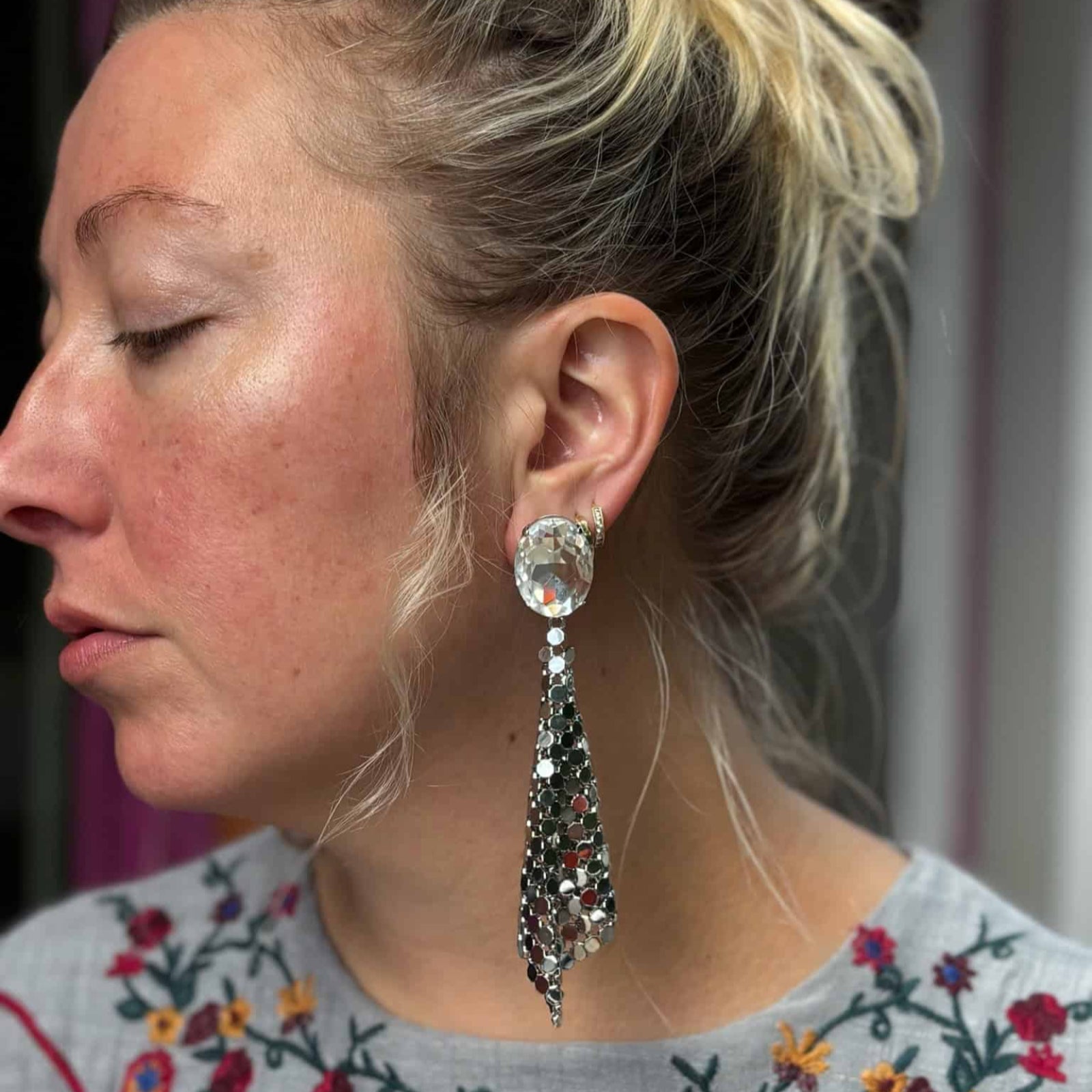 Model wearing silver glo mesh earrings against floral top
