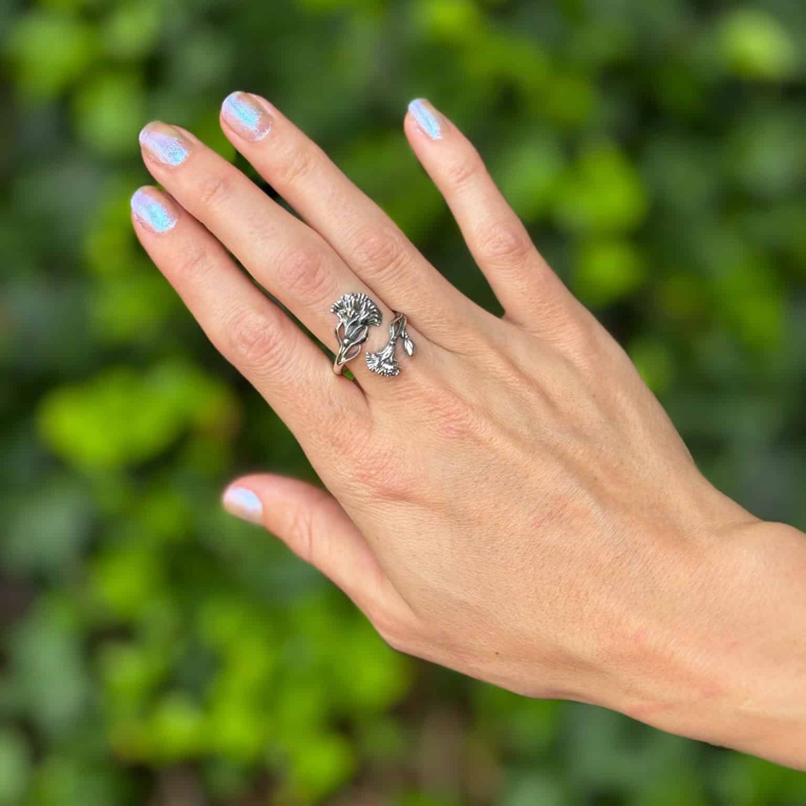 Hand wearing a ring with a green leafy background