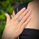Hand with a silver ring on a blurred green background
