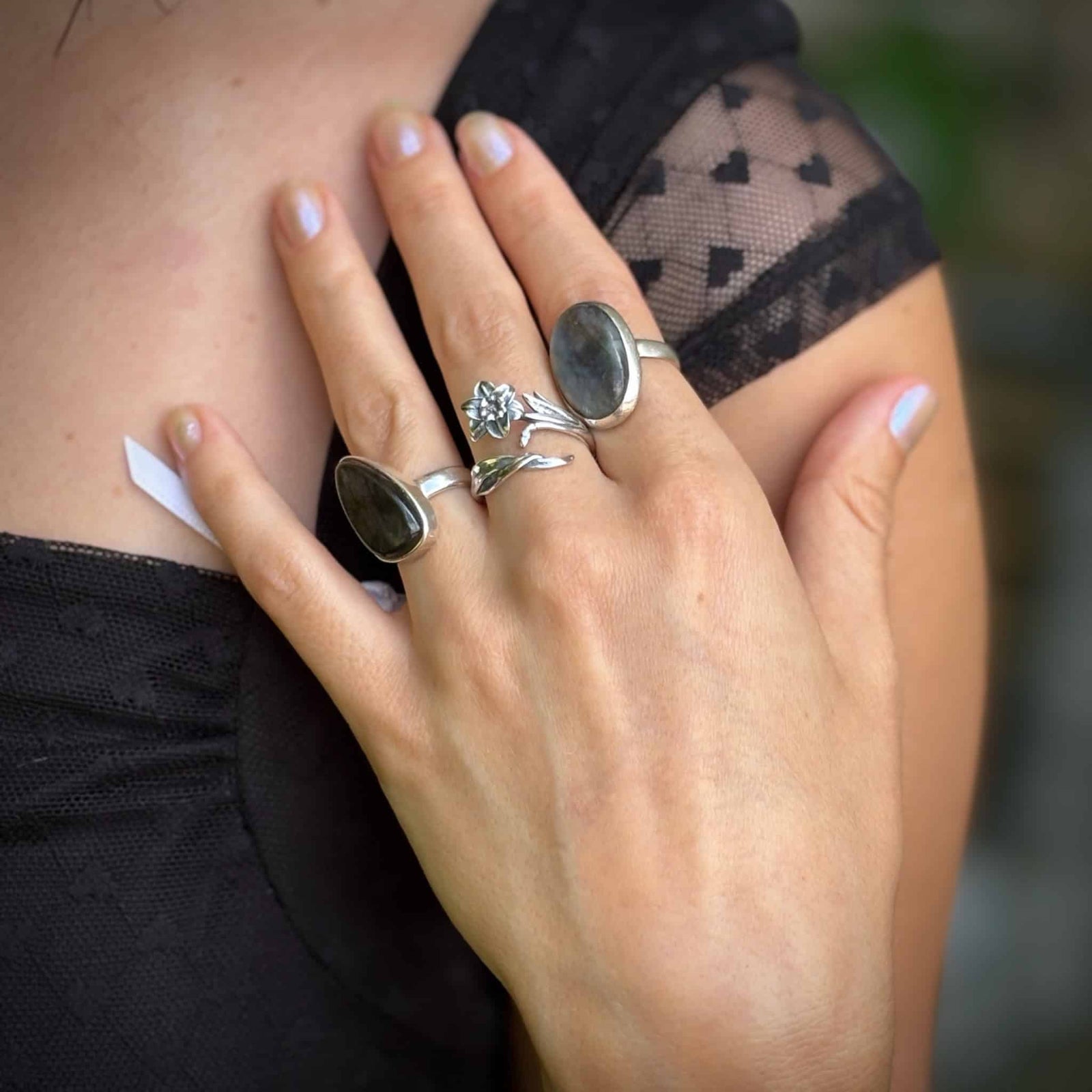 Close-up of a hand wearing multiple rings with a blurred background