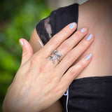Close-up of a hand with a silver ring on a blurred green background