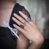 Close-up of a hand wearing multiple rings with a blurred background