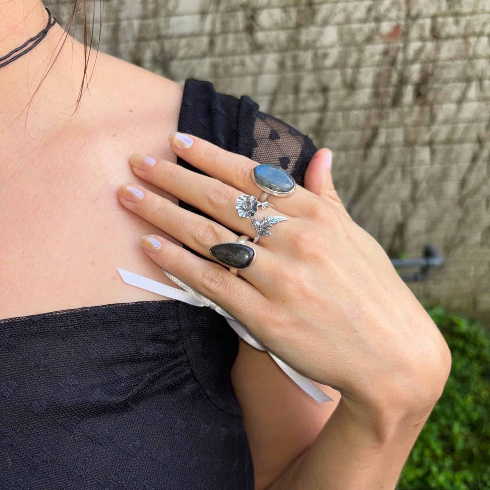 Person wearing multiple rings on a blurred outdoor background